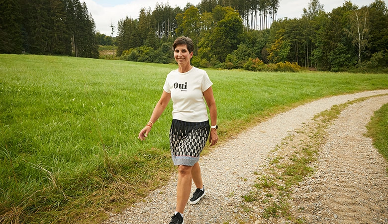 Eine Frau läuft einen Feldweg entlang. 