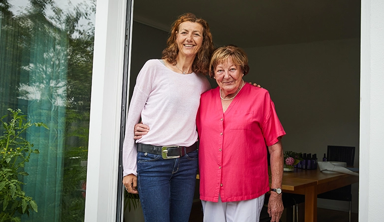 Zwei Frauen stehen nebeneinander in einer geöffneten Terrassentür.